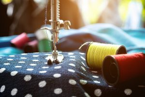 Close up of a sewing machine with fabrics and spools of thread.