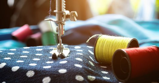 Close up of a sewing machine with fabrics and spools of thread.